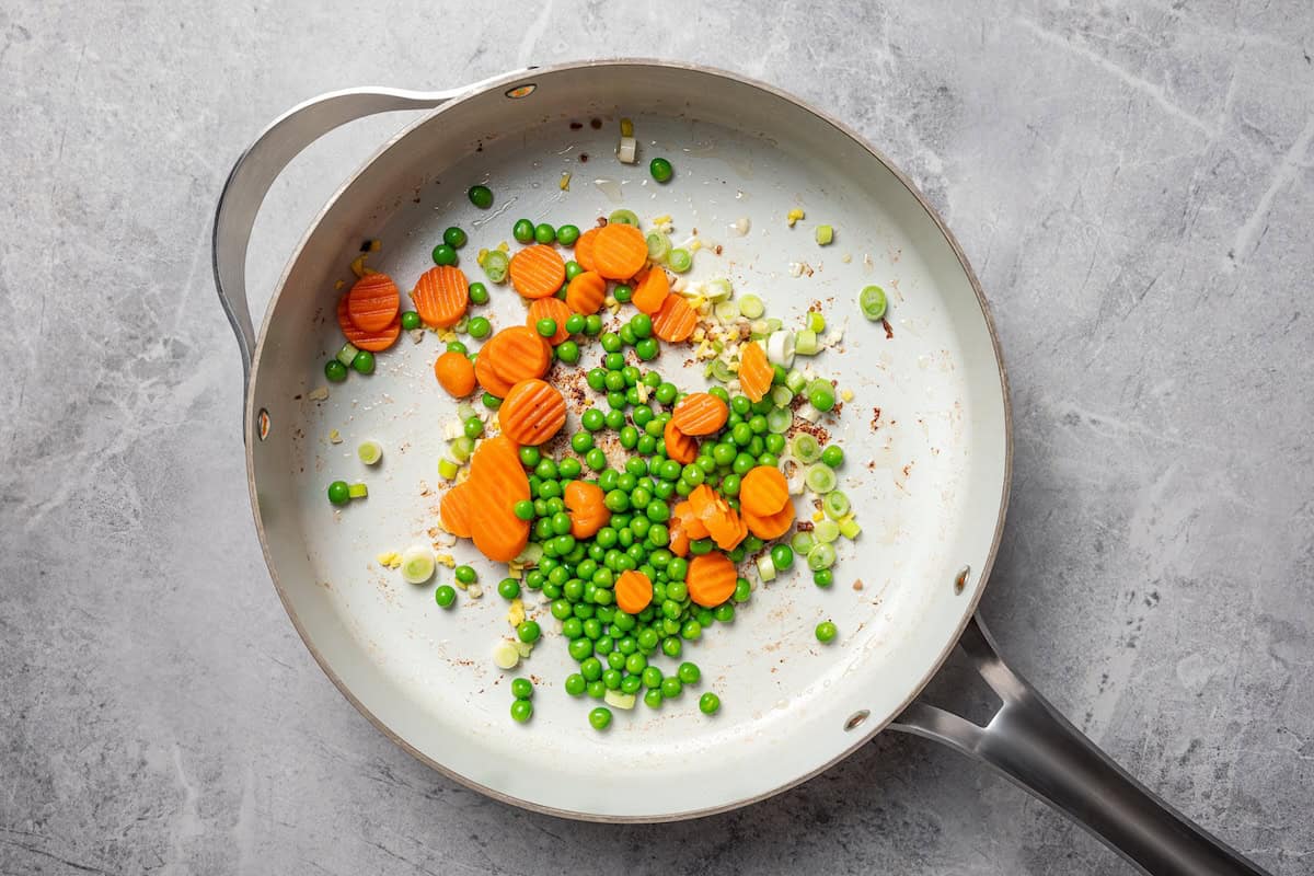 Pork fried rice is a quick, one-pan dinner packed with crispy ground pork, cooked eggs, and veggies. It's the best way to use up day-old rice! Aromatics, vegetables, and peas sautéed in a skillet.