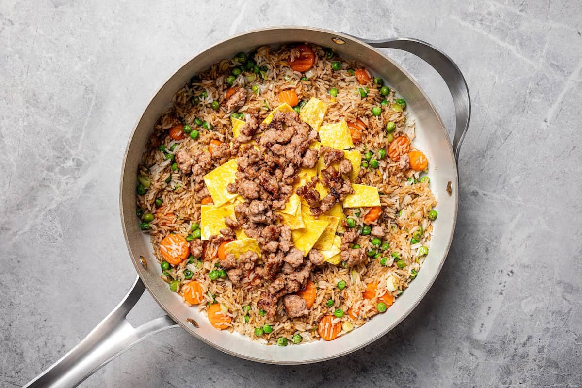 Pork fried rice is a quick, one-pan dinner packed with crispy ground pork, cooked eggs, and veggies. It's the best way to use up day-old rice! Fried pork, eggs, and sauce added to fried rice with vegetables in a skillet.