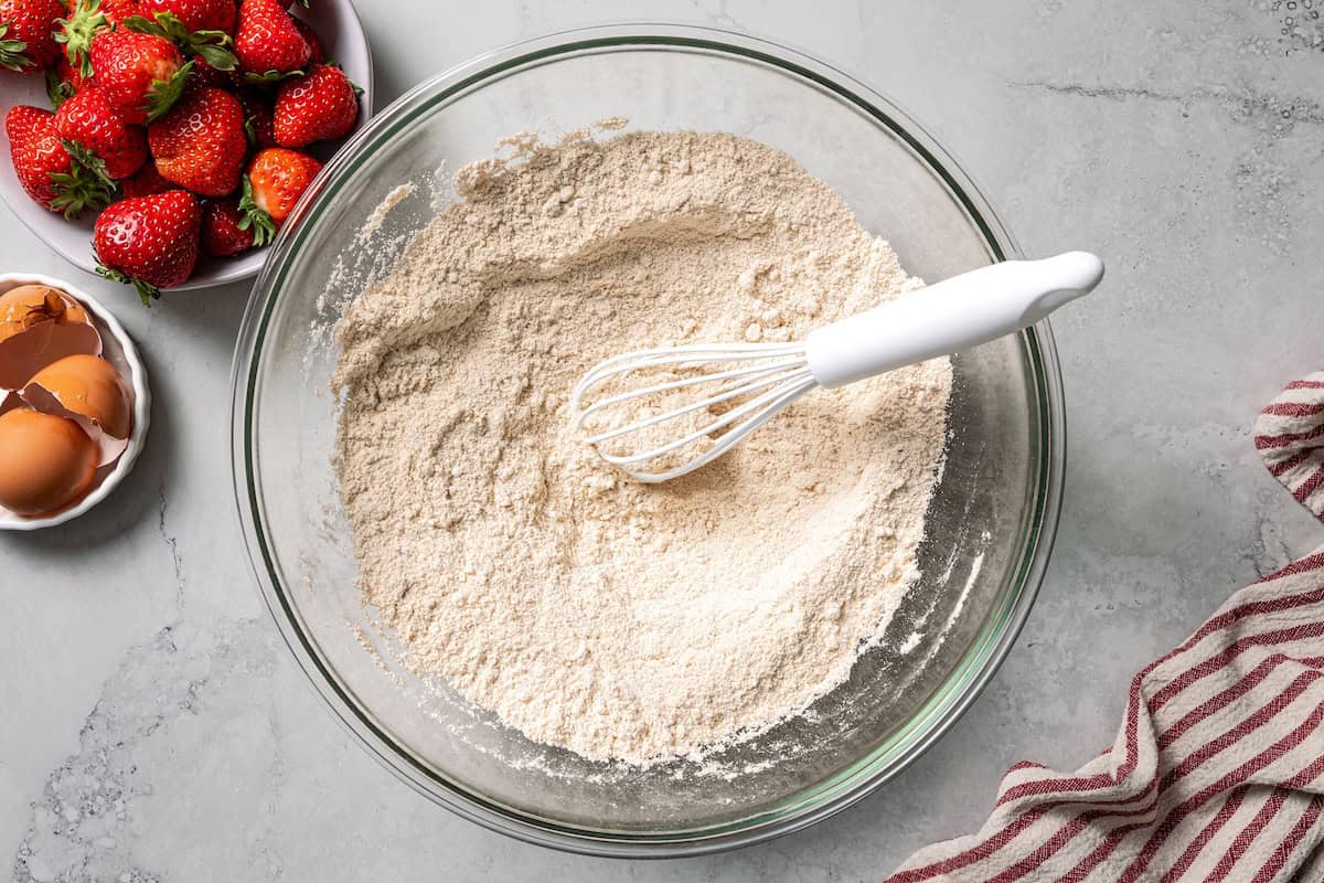 These moist strawberry protein muffins with applesauce, cottage cheese, and protein powder make an easy, light breakfast or meal prep snack! Dry ingredients whisked together in a bowl.