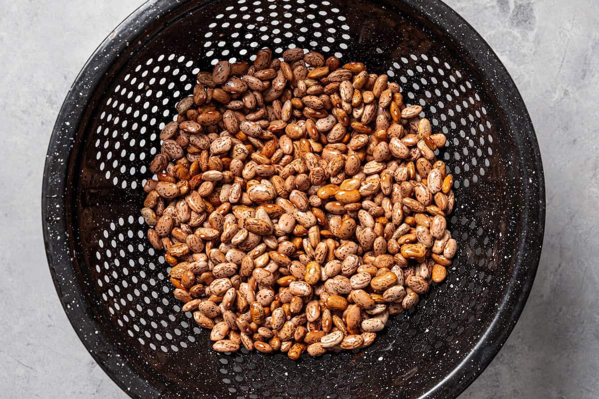 Slow cooker pinto beans are full of flavor and so easy to make. Add dry beans to the crock pot in the morning, and they’re tender by dinner! Rinsed dry pinto beans in a colander.