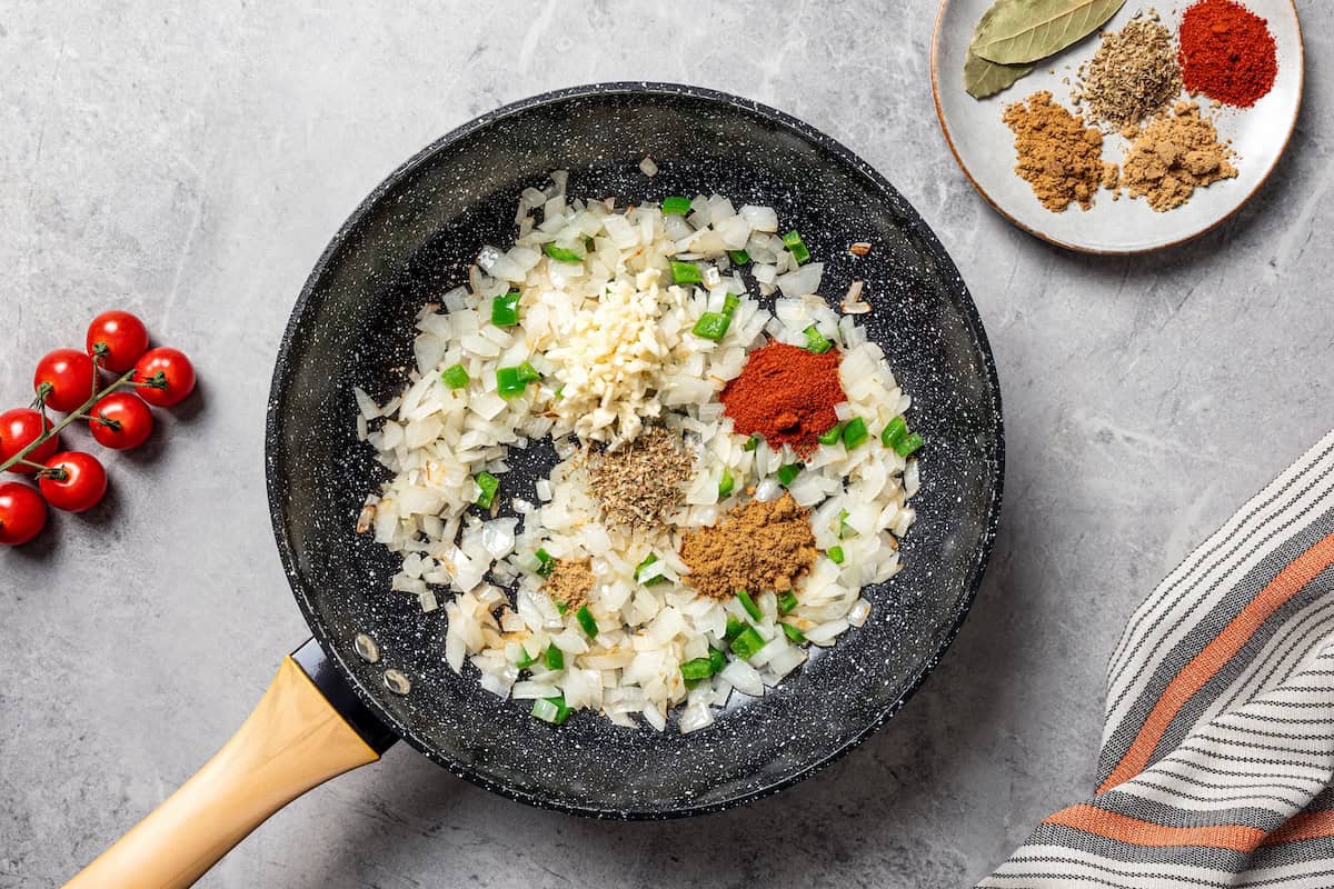 Slow cooker pinto beans are full of flavor and so easy to make. Add dry beans to the crock pot in the morning, and they’re tender by dinner! Seasonings added to sautéed onions in a skillet.