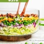 A seven layer salad in a glass salad bowl.