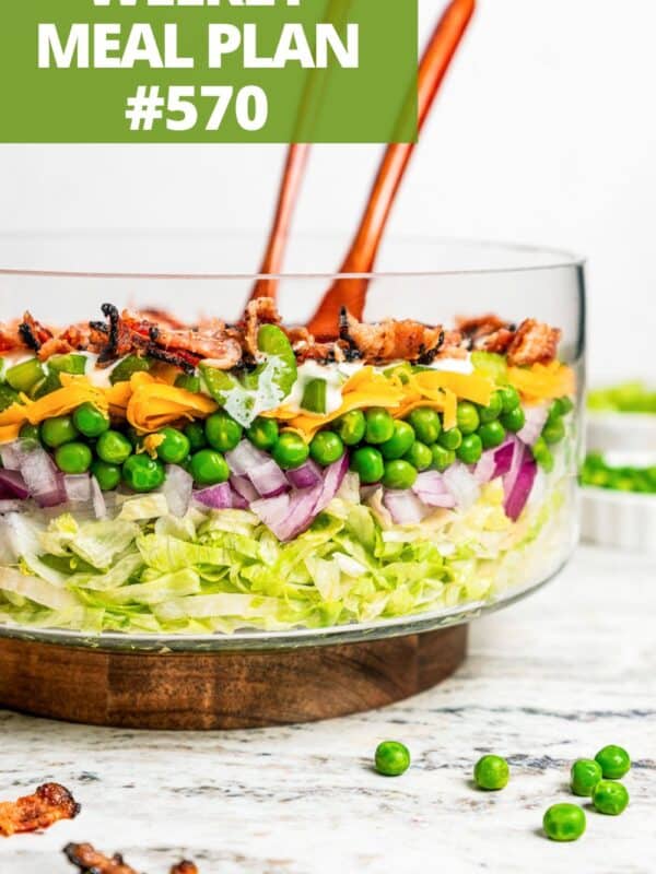 A seven layer salad in a glass salad bowl.