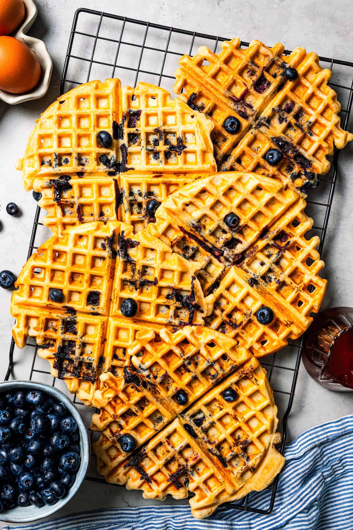 These classic blueberry waffles are light, fluffy, and ready in minutes. Rest the batter, then cook until they're golden brown and crisp. Crisp blueberry waffles on a wire rack.