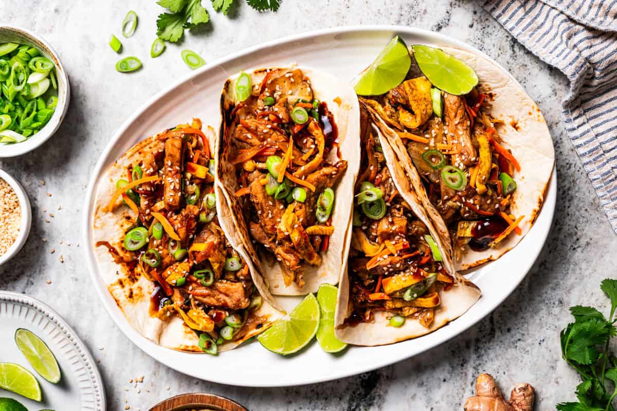 Craving moo shu pork for dinner? This homemade copycat is better than takeout and ready in 25 minutes with pork, veggies, and savory sauce. Moo shu pork wraps served on a platter.