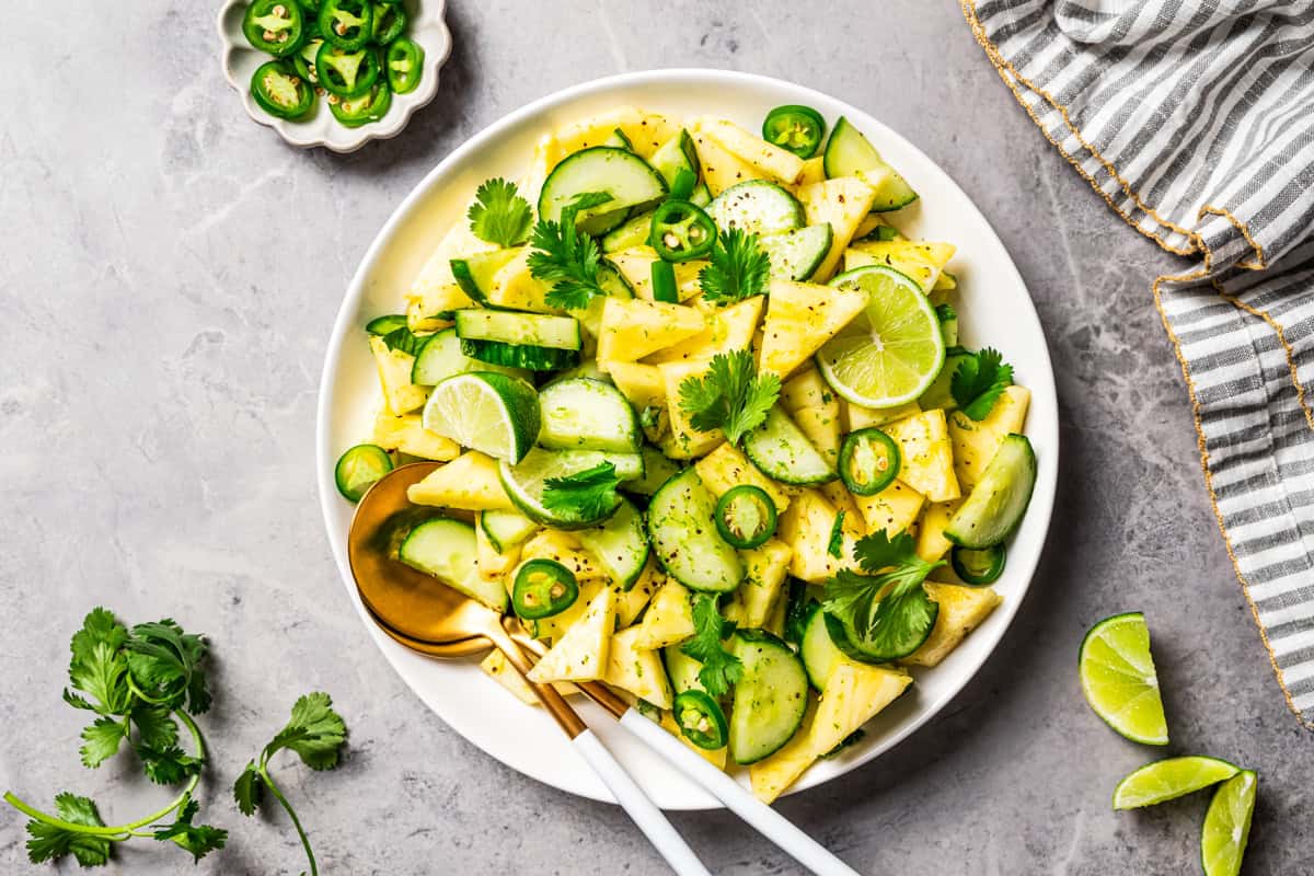 This refreshing pineapple cucumber salad is an easy side salad with fresh pineapple, crisp cucumber, spicy jalapeños, cilantro, and lime. Pineapple cucumber salad served in a bowl, garnished with fresh cilantro and lime wedges.