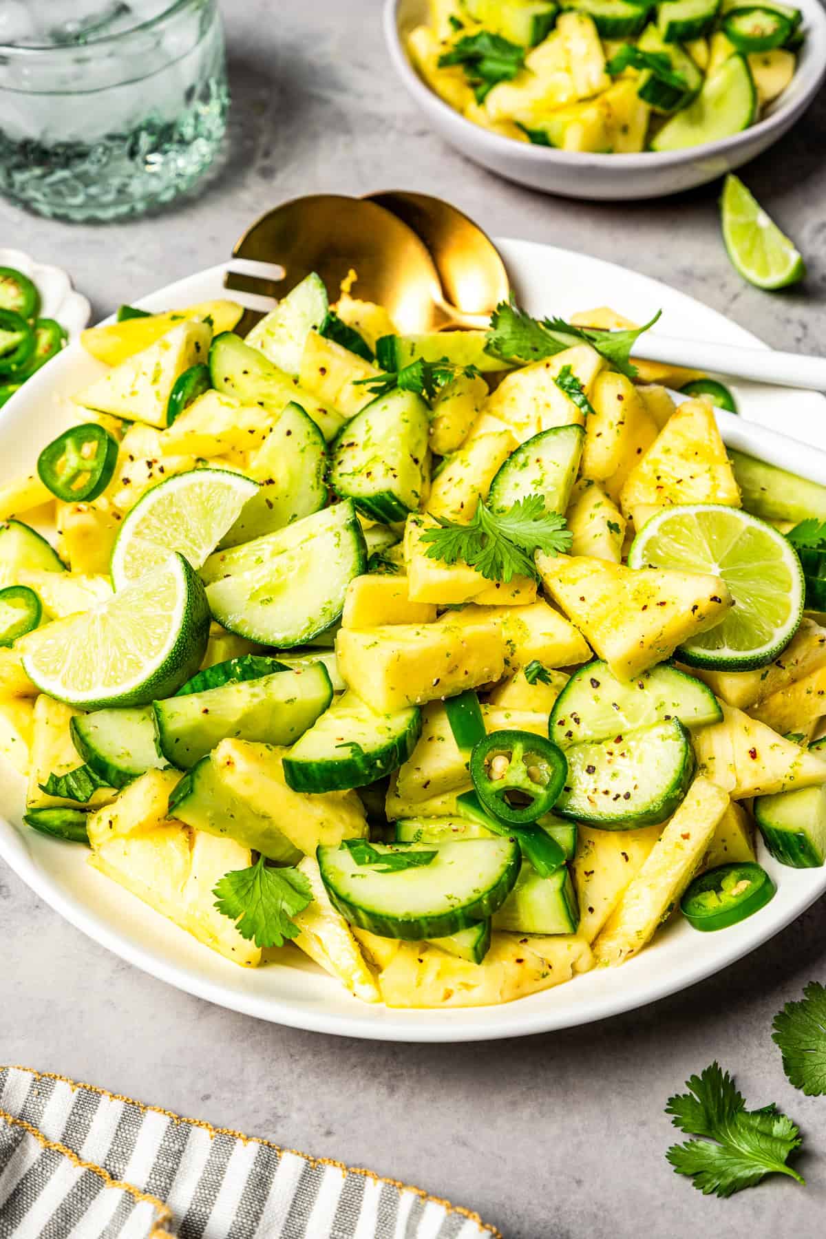 This refreshing pineapple cucumber salad is an easy side salad with fresh pineapple, crisp cucumber, spicy jalapeños, cilantro, and lime. Cubed pineapples and cucumber slices in a salad bowl, garnished with lime and cilantro.