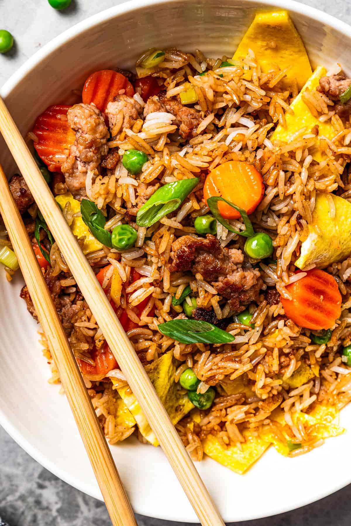 Pork fried rice is a quick, one-pan dinner packed with crispy ground pork, cooked eggs, and veggies. It's the best way to use up day-old rice! Homemade pork fried rice served in a bowl with a set of chopsticks on the side.