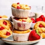 Three strawberry protein muffins stacked on a plate.
