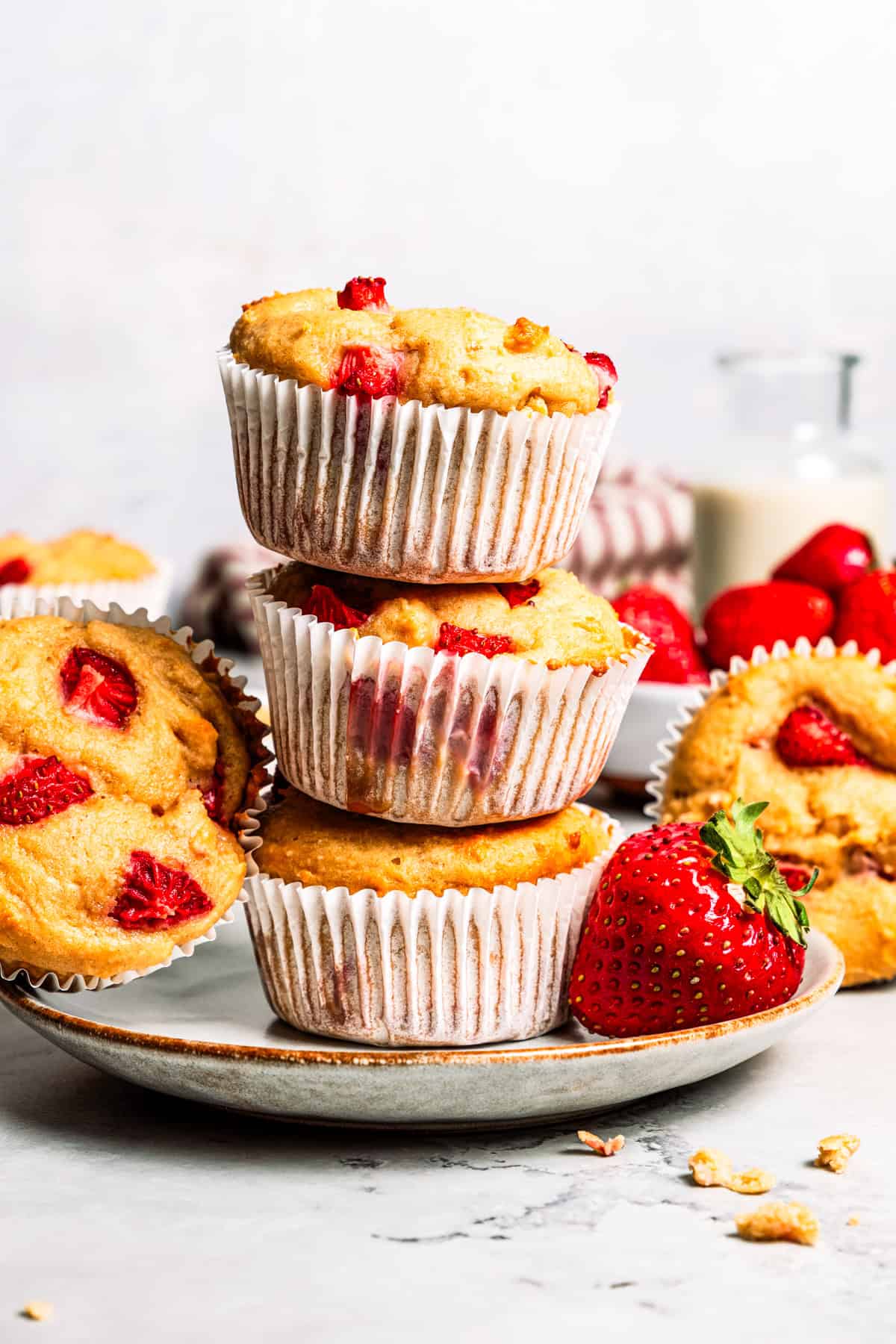 These moist strawberry protein muffins with applesauce, cottage cheese, and protein powder make an easy, light breakfast or meal prep snack! Three strawberry protein muffins stacked on a plate.