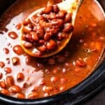 A spoon scooping pinto beans from the slow cooker.