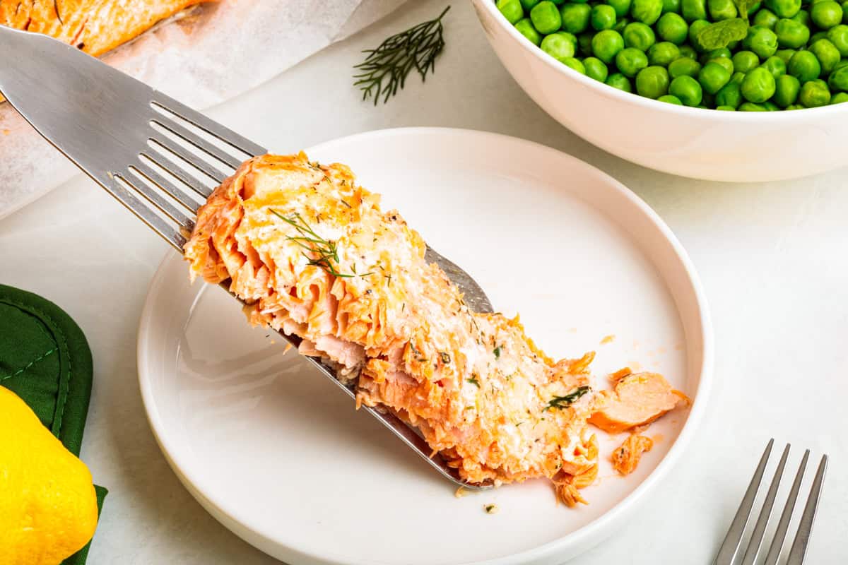 Baked steelhead trout with lemon, butter, garlic, and fresh dill. This easy steelhead trout recipe is tender, flaky, and ready in 30 minutes. A fish spatula is placed down a serving of a steelhead trout fillet on a dinner plate.