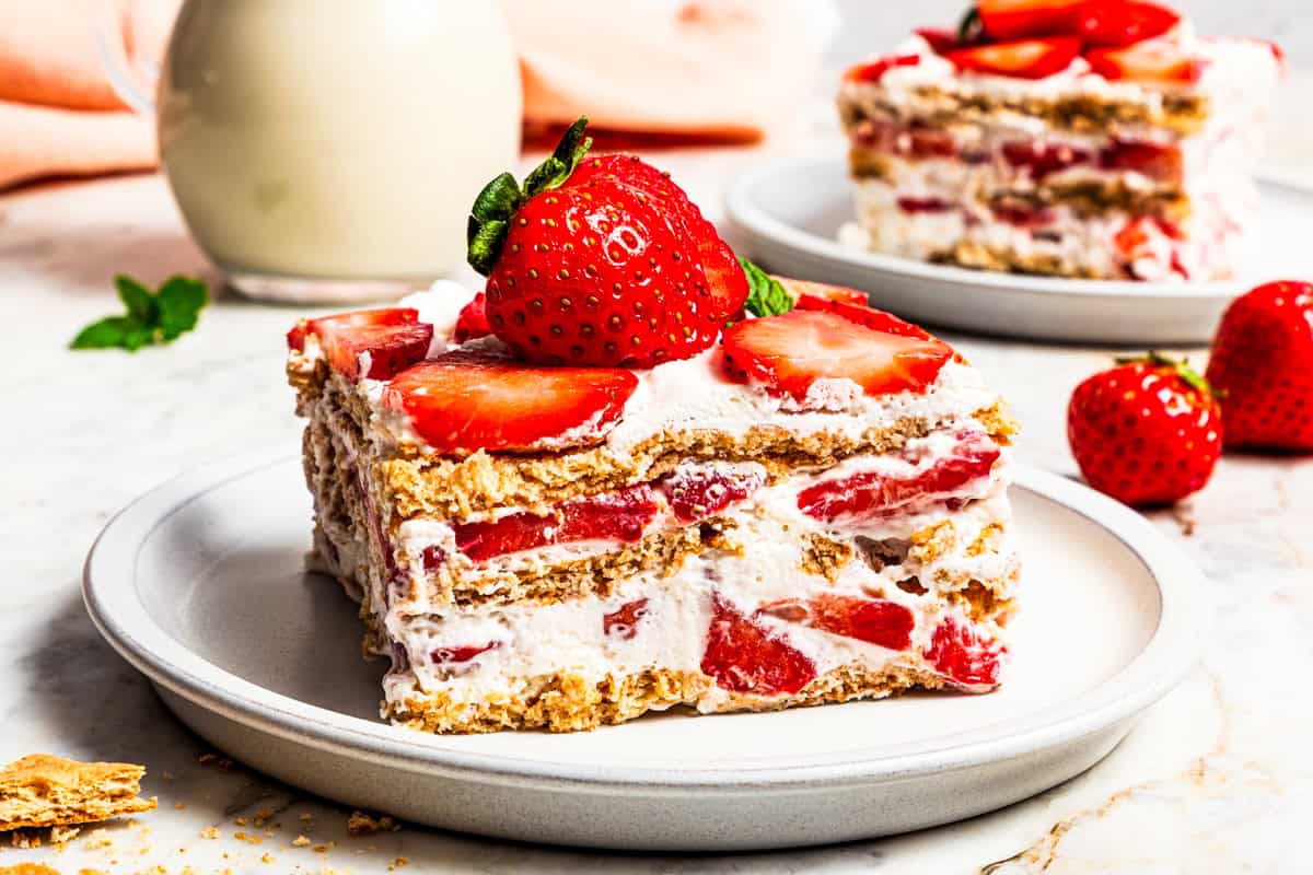 This no-bake strawberry icebox cake is an easy overnight dessert with layers of graham crackers, fresh strawberries, and fluffy whipped cream. A slice of strawberry icebox cake served on a plate.