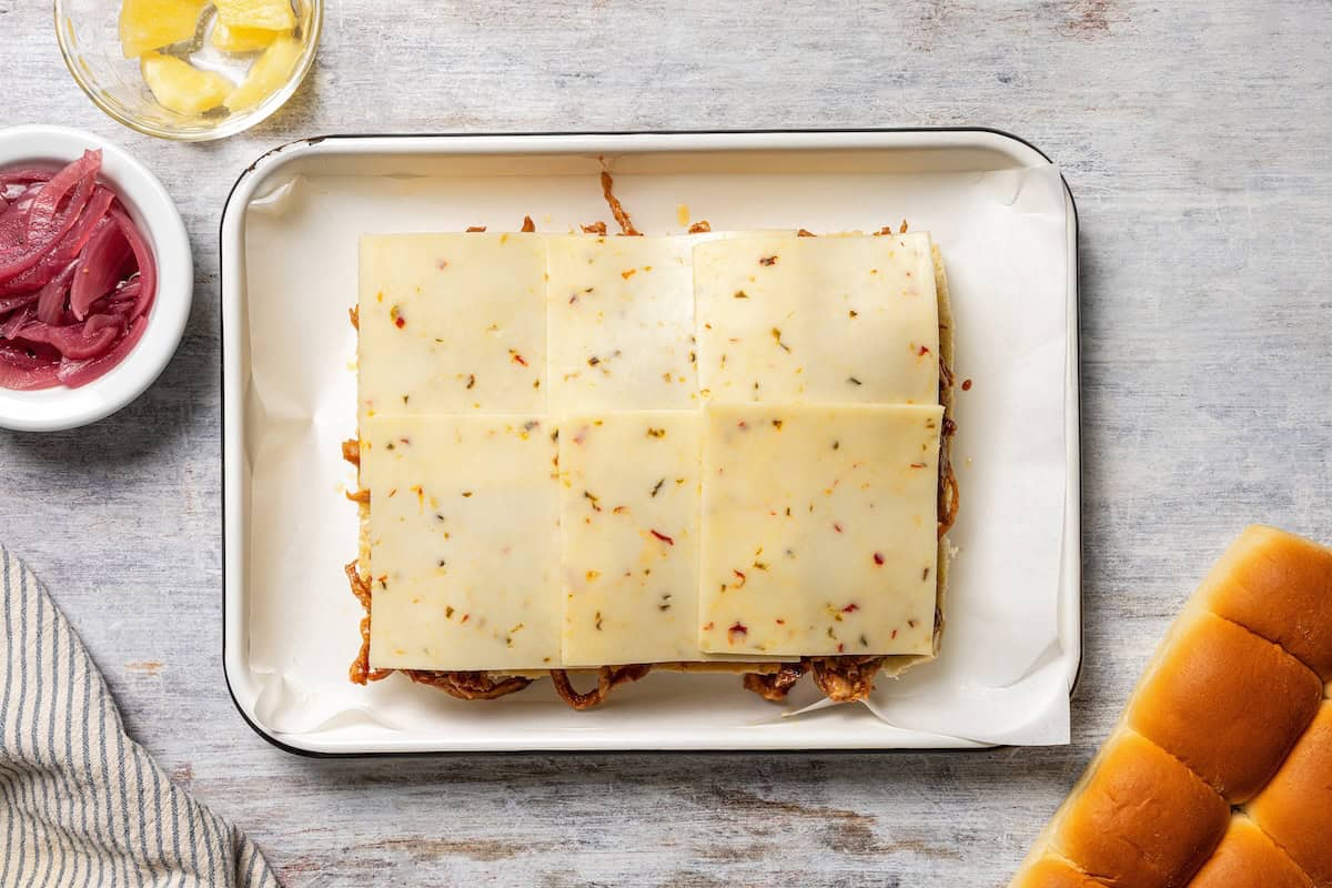 These BBQ pulled pork sliders are sweet, smoky, savory, and easy to make with leftover pulled pork, melted cheese, and fluffy Hawaiian rolls. Slices of pepper jack cheese layered over pulled pork and pineapple on Hawaiian rolls.