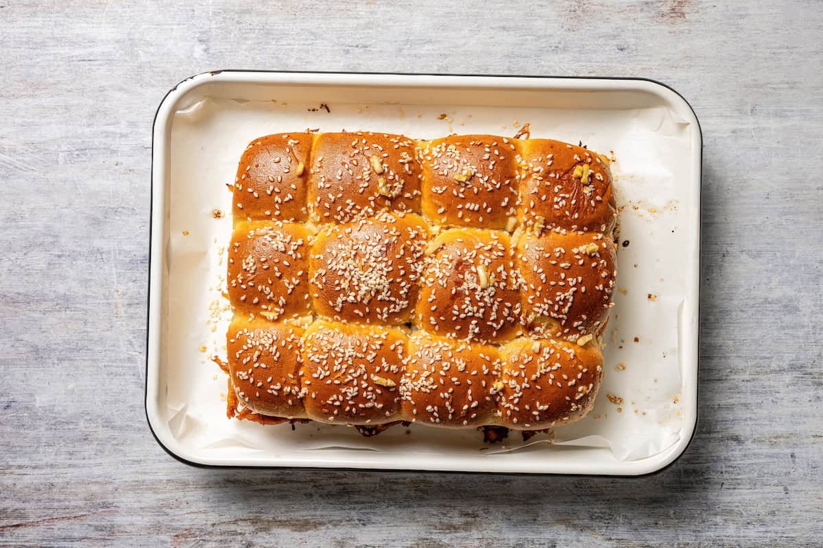 These BBQ pulled pork sliders are sweet, smoky, savory, and easy to make with leftover pulled pork, melted cheese, and fluffy Hawaiian rolls. Overhead view of baked pulled pork sliders on a sheet pan.