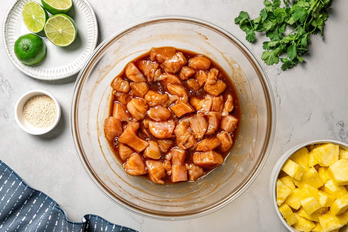 Chicken pieces marinating in a bowl with sweet, spicy chicken marinade.