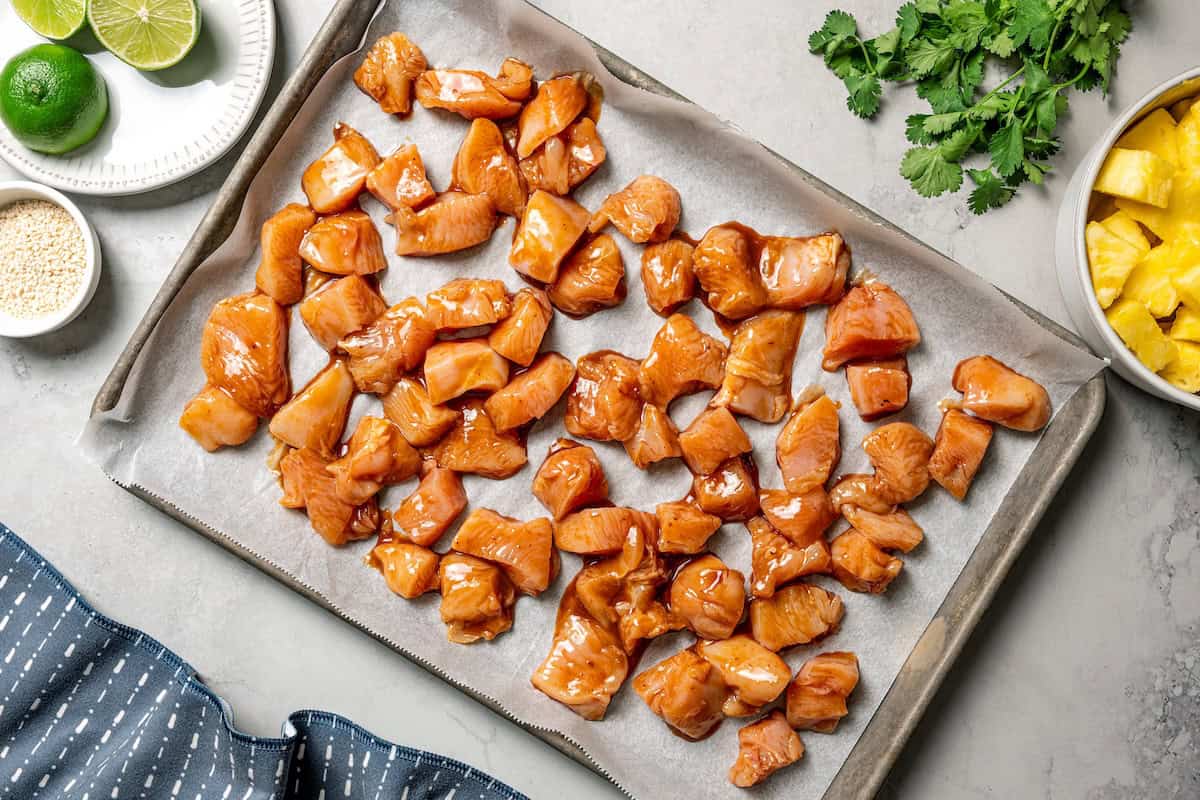 Marinated chicken pieces on a baking sheet.