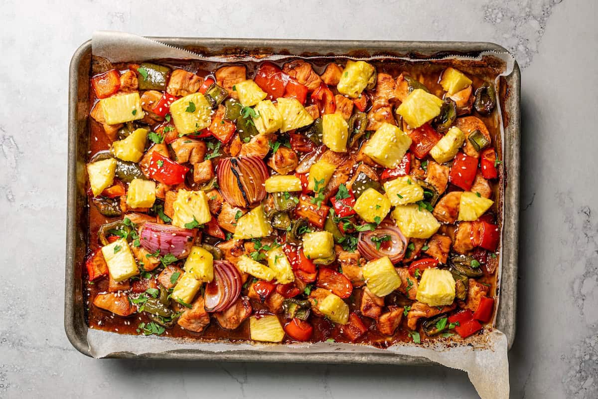 Overhead view of roasted sheet pan Hawaiian chicken with veggies on a baking sheet.