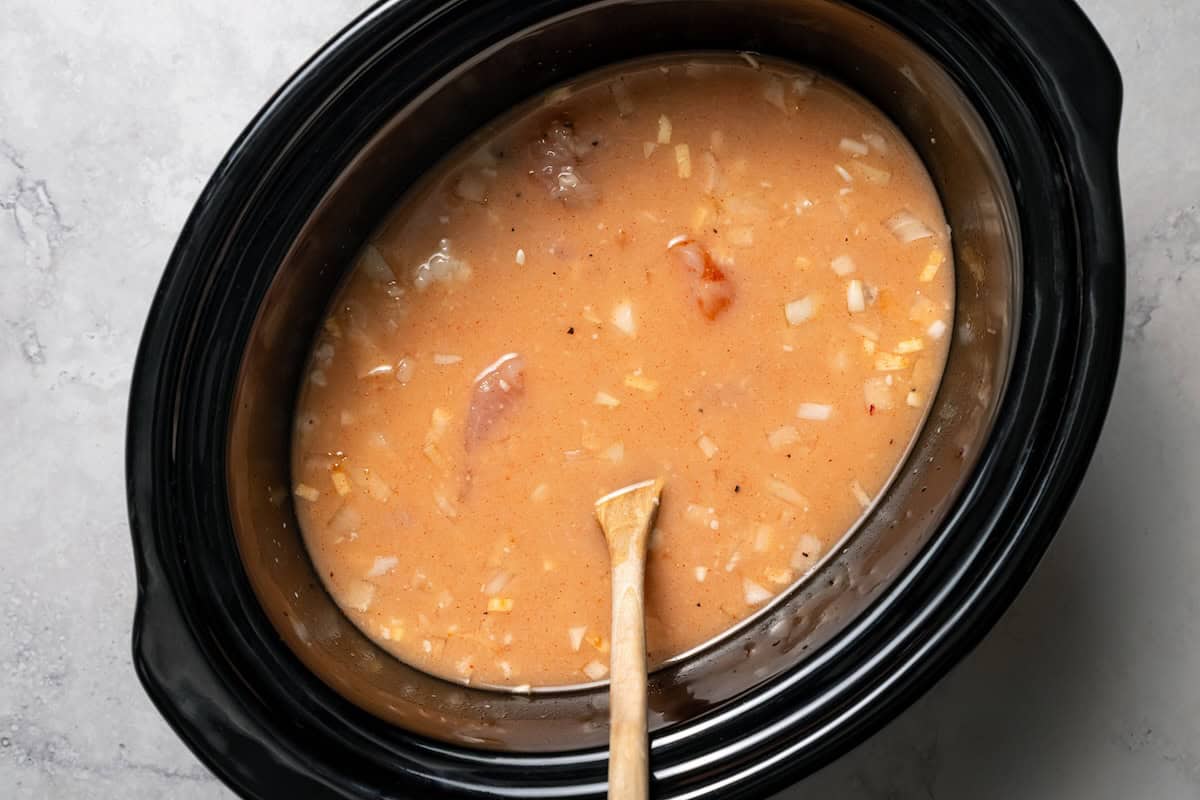 Creamy slow cooker chicken and rice is an easy one-pot dinner with rice, condensed mushroom soup, melty cheddar, onions, and juicy chicken. Cream of mushroom chicken and rice ingredients combined inside the slow cooker.