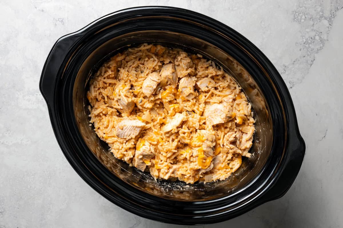 Creamy slow cooker chicken and rice is an easy one-pot dinner with rice, condensed mushroom soup, melty cheddar, onions, and juicy chicken. Cream of mushroom chicken and rice inside the slow cooker.