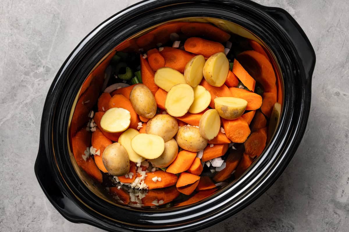 This tender, juicy slow cooker pork shoulder needs only 10 minutes of prep! It's slowly braised with hearty veggies for a cozy one-pot meal. Chopped potatoes, carrots, and celery added to the slow cooker.