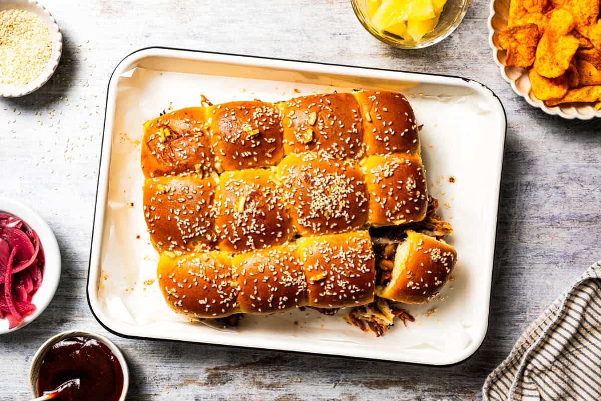 These BBQ pulled pork sliders are sweet, smoky, savory, and easy to make with leftover pulled pork, melted cheese, and fluffy Hawaiian rolls. Pulled pork sliders in a baking pan.