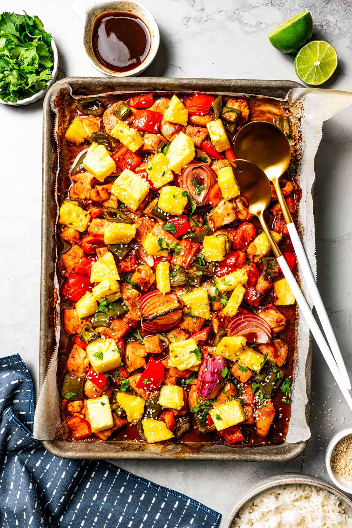 A baking sheet of chicken bites with bell peppers, red onions, and pineapple to make sheet pan Hawaiian chicken.