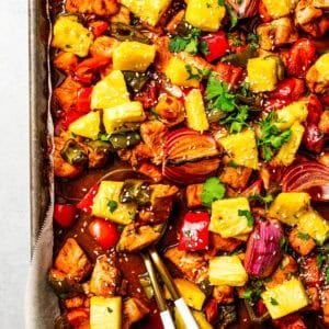 A baking sheet of chicken bites with bell peppers, red onions, and pineapple to make Hawaiian chicken.