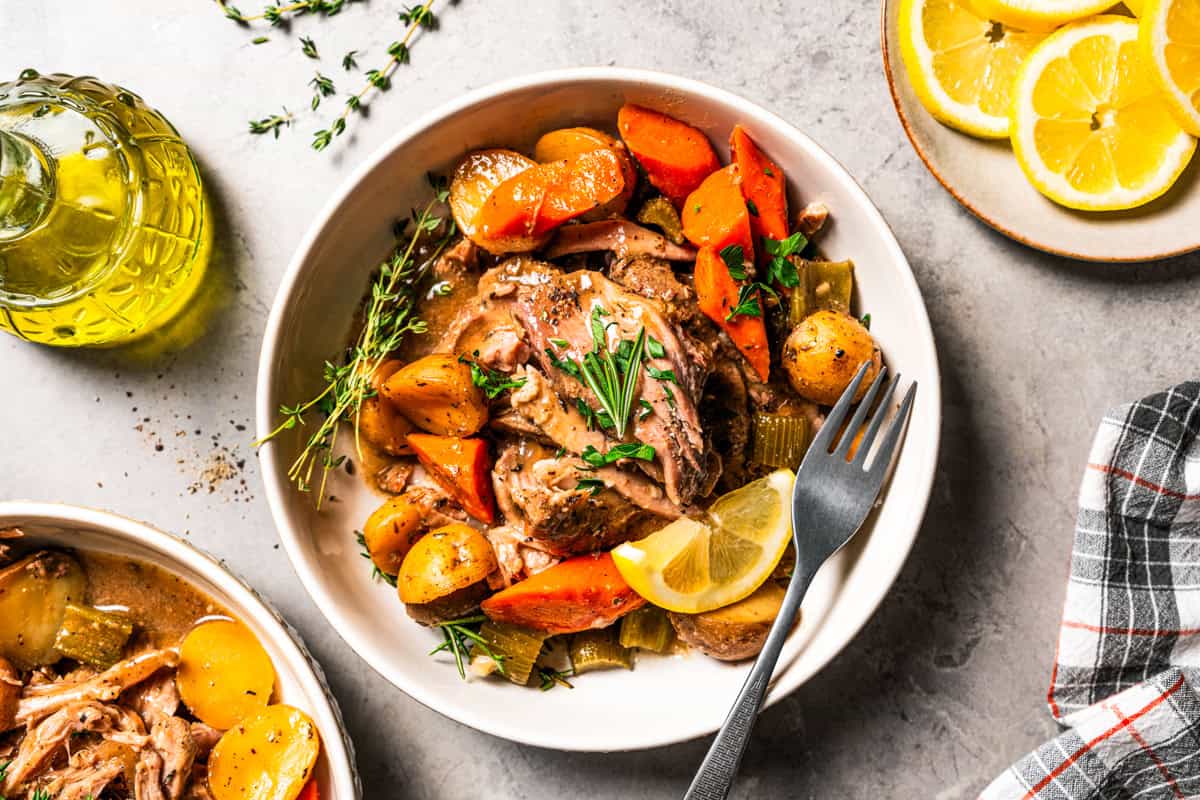 This tender, juicy slow cooker pork shoulder needs only 10 minutes of prep! It's slowly braised with hearty veggies for a cozy one-pot meal. Slow-cooked pork shoulder and veggies served in a bowl.