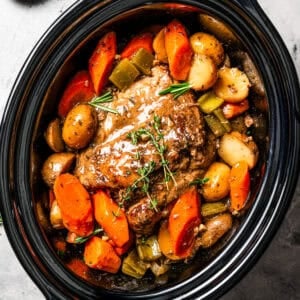 Cooked pork shoulder in the slow cooker with carrots and potatoes.