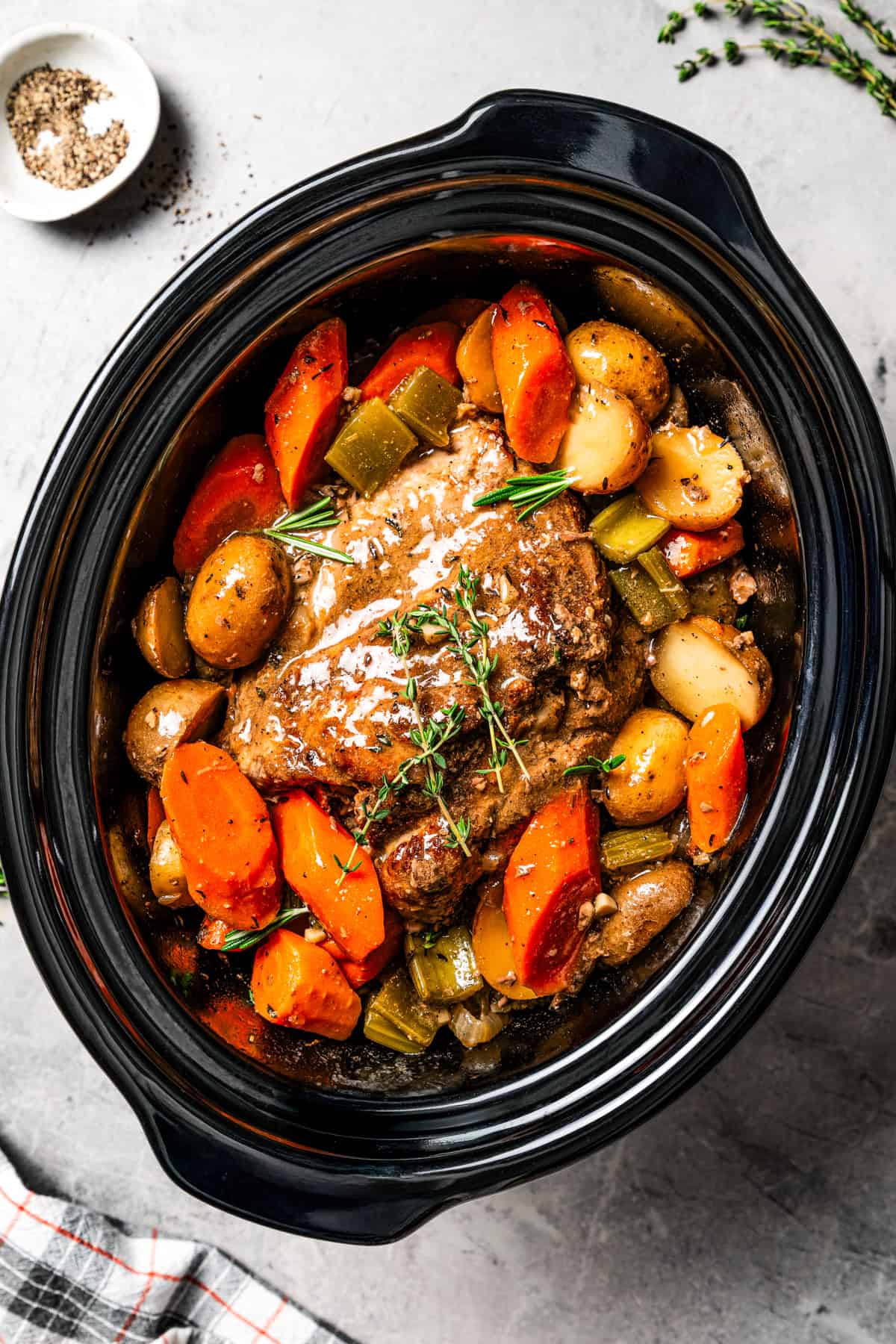 This tender, juicy slow cooker pork shoulder needs only 10 minutes of prep! It's slowly braised with hearty veggies for a cozy one-pot meal. Cooked pork shoulder in the slow cooker with carrots and potatoes.