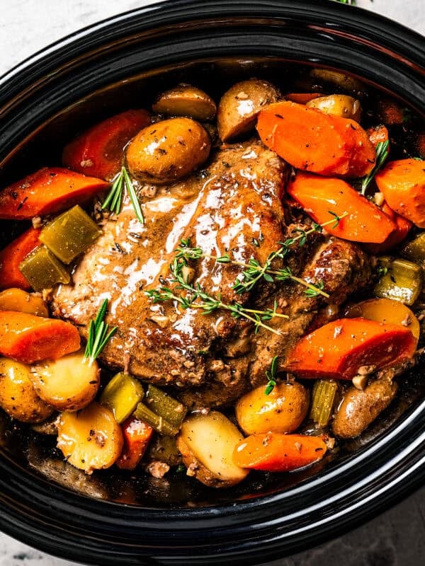Cooked pork shoulder in the slow cooker with carrots and potatoes.