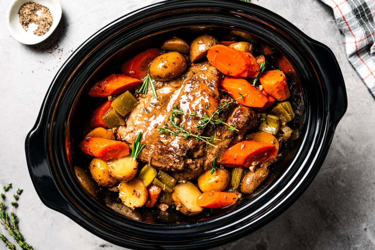 This tender, juicy slow cooker pork shoulder needs only 10 minutes of prep! It's slowly braised with hearty veggies for a cozy one-pot meal. Cooked pork shoulder in the slow cooker with carrots and potatoes.