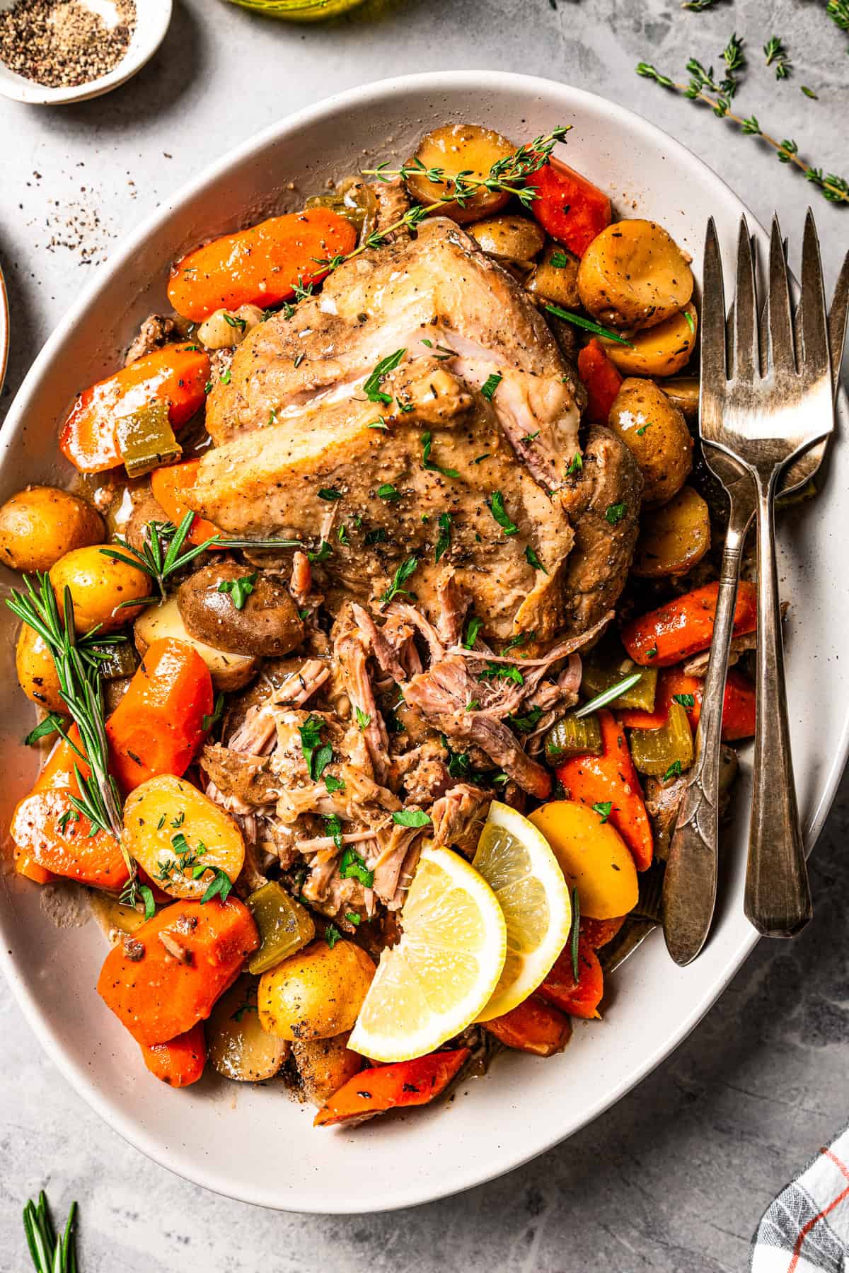 This tender, juicy slow cooker pork shoulder needs only 10 minutes of prep! It's slowly braised with hearty veggies for a cozy one-pot meal. Juicy slow cooker pork shoulder and vegetables served on a platter with two forks.