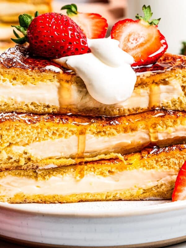 A stack of cream cheese stuffed French toast slices topped with strawberries.