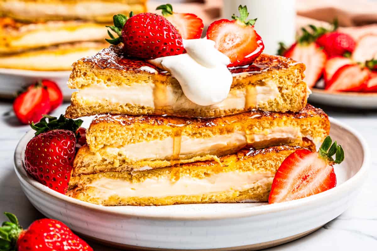Make this cream cheese stuffed French toast with thick slices of custard-dipped brioche filled with sweet mascarpone and fresh lemon zest. A stack of cream cheese stuffed French toast slices topped with strawberries.