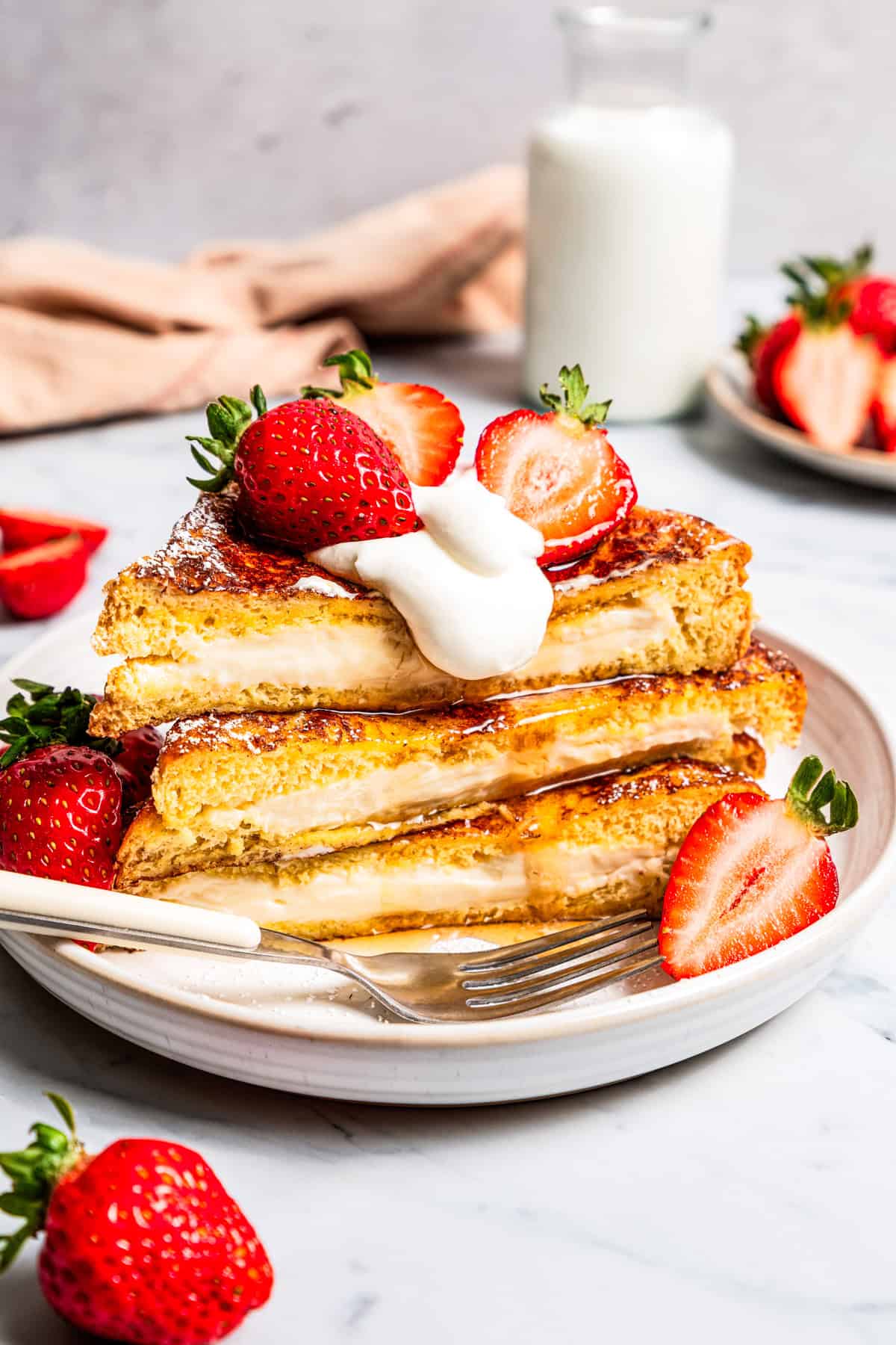 Make this cream cheese stuffed French toast with thick slices of custard-dipped brioche filled with sweet mascarpone and fresh lemon zest. A stack of cream cheese stuffed French toast served on a plate.