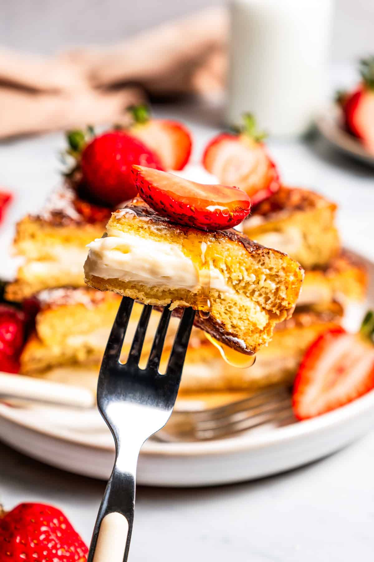 Make this cream cheese stuffed French toast with thick slices of custard-dipped brioche filled with sweet mascarpone and fresh lemon zest. A fork holding up a bite of cream cheese stuffed French toast.