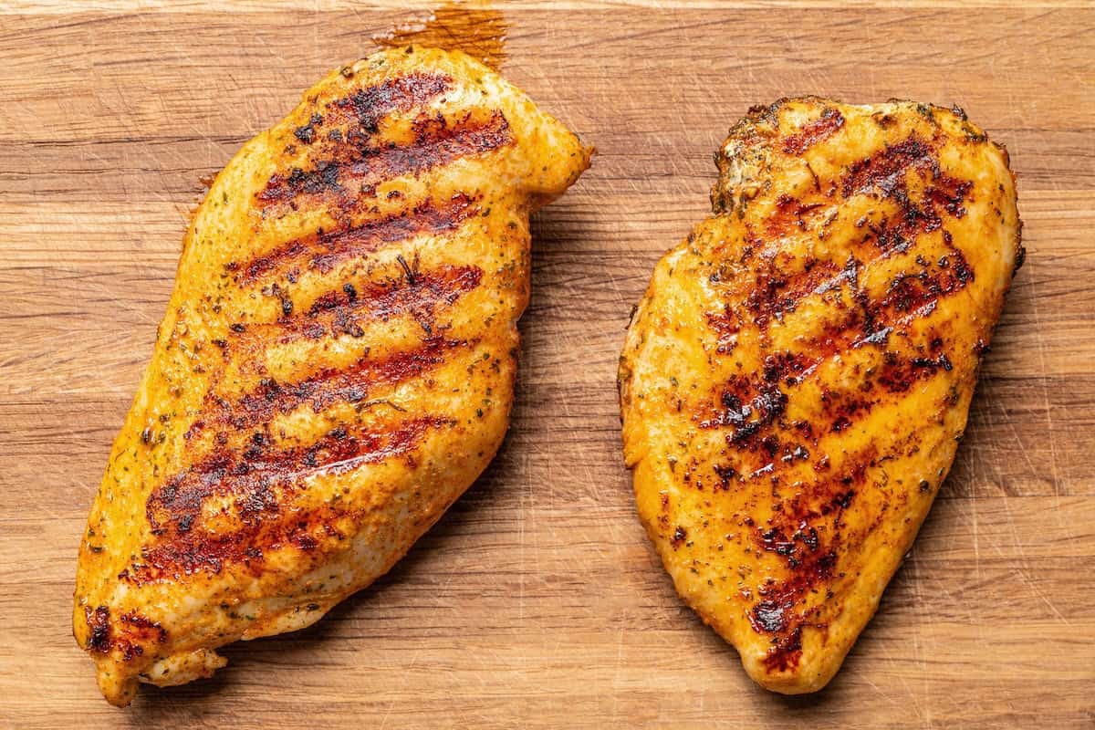 This easy BLT chicken salad combines juicy grilled chicken, crispy bacon, and ripe tomatoes with fresh lettuce and creamy yogurt dressing. Perfectly grilled chicken breasts with grill marks on a wooden cutting board.