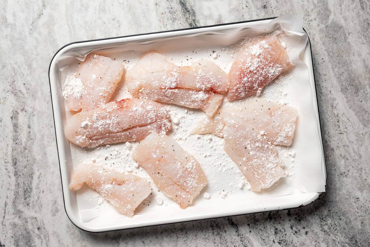 Make beer-battered fish with easy ingredients! This crispy, flaky fried white fish is perfect for tacos, pub-style fish and chips, and more. Fish fillets lightly coated with flour on a sheet pan.