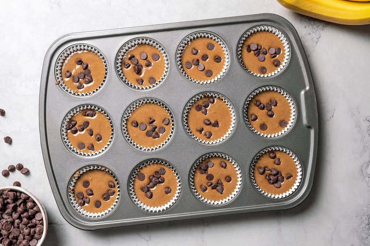 Chocolate protein muffins are moist, loaded with hidden veggies, and easy to make in the blender for a high-protein breakfast or meal prep. Chocolate muffin batter divided between the wells of a muffin pan.