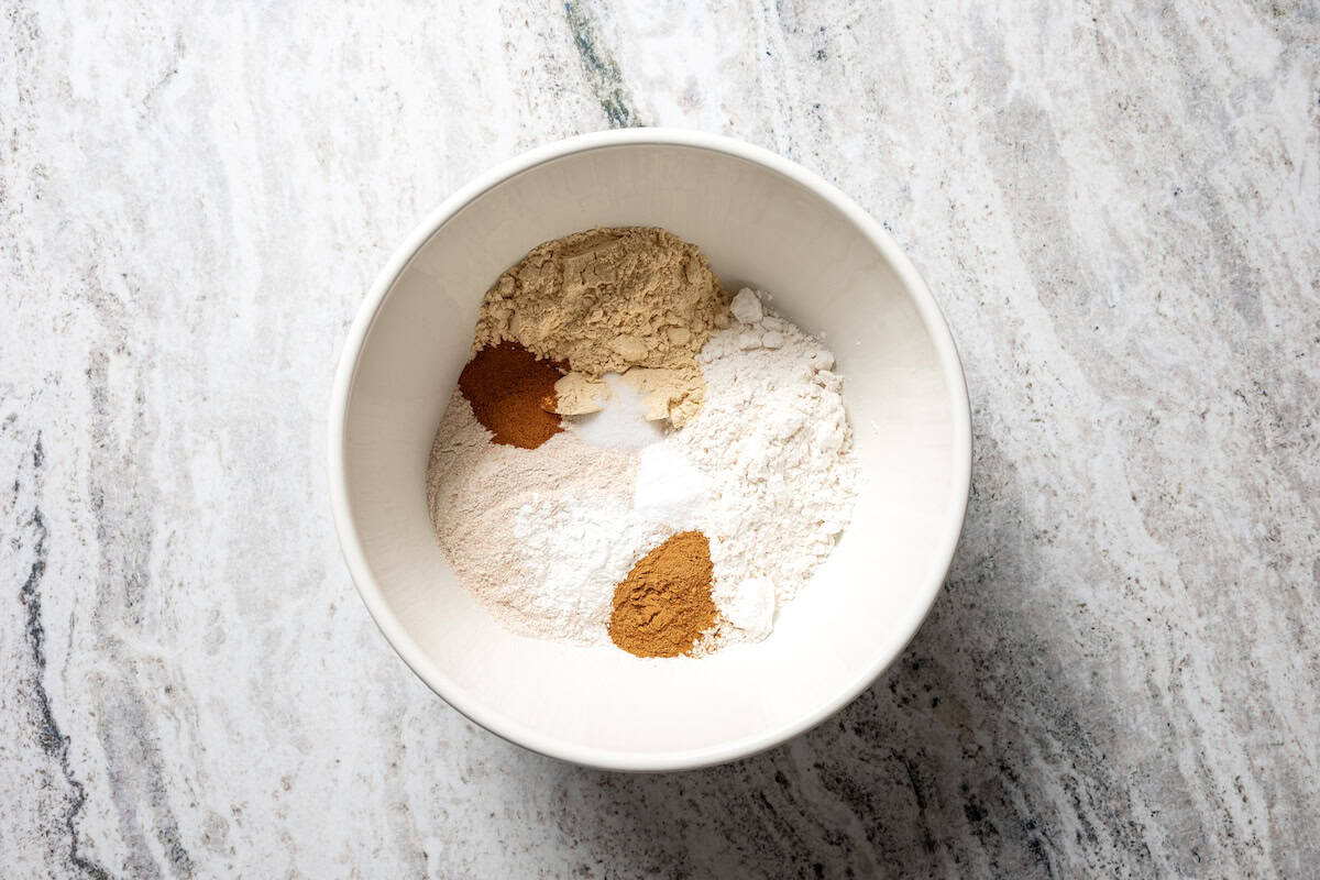 Moist, fluffy pumpkin protein muffins are a high-protein fall treat made with vanilla whey powder, Greek yogurt, eggs, and pumpkin purée. Dry ingredients combined in a bowl.