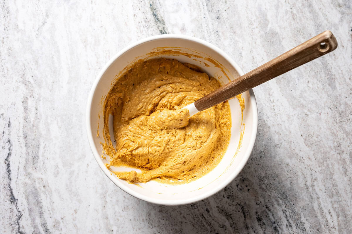 Moist, fluffy pumpkin protein muffins are a high-protein fall treat made with vanilla whey powder, Greek yogurt, eggs, and pumpkin purée. Pumpkin muffin batter in a bowl.