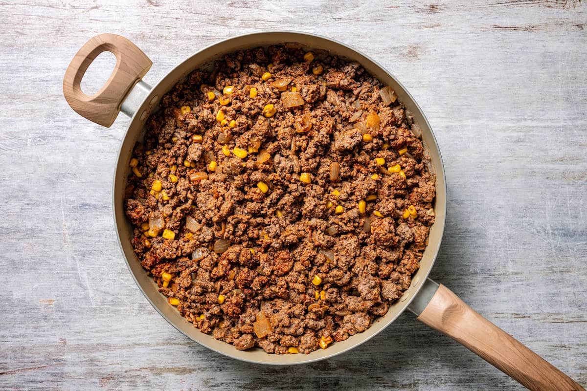 Baked sheet pan tacos are an easy way to make tacos for a crowd with crispy tortillas, seasoned ground beef, melty cheese, and pico de gallo. Seasoned ground taco beef in a skillet.