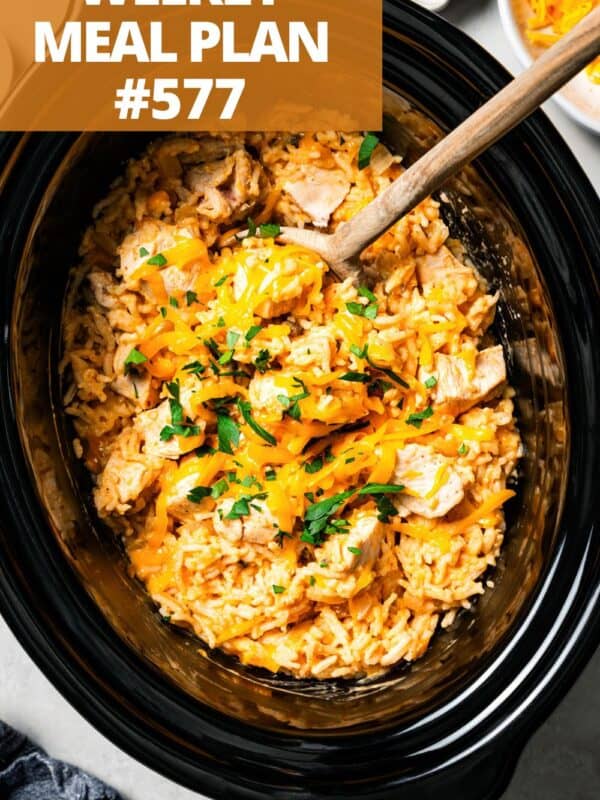 A wooden spoon stirring through chicken and rice in the slow cooker.