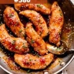 A skillet of chicken tenders in a honey garlic sauce and garnished with sesame seeds.