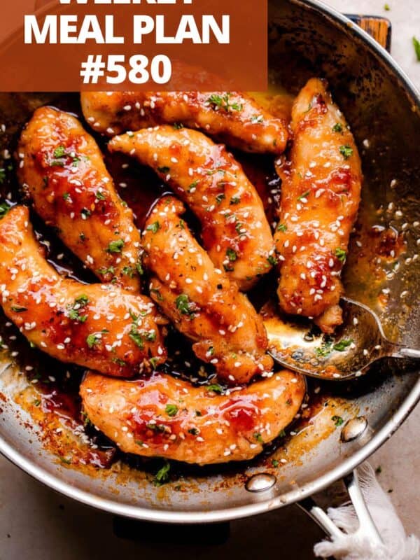 A skillet of chicken tenders in a honey garlic sauce and garnished with sesame seeds.