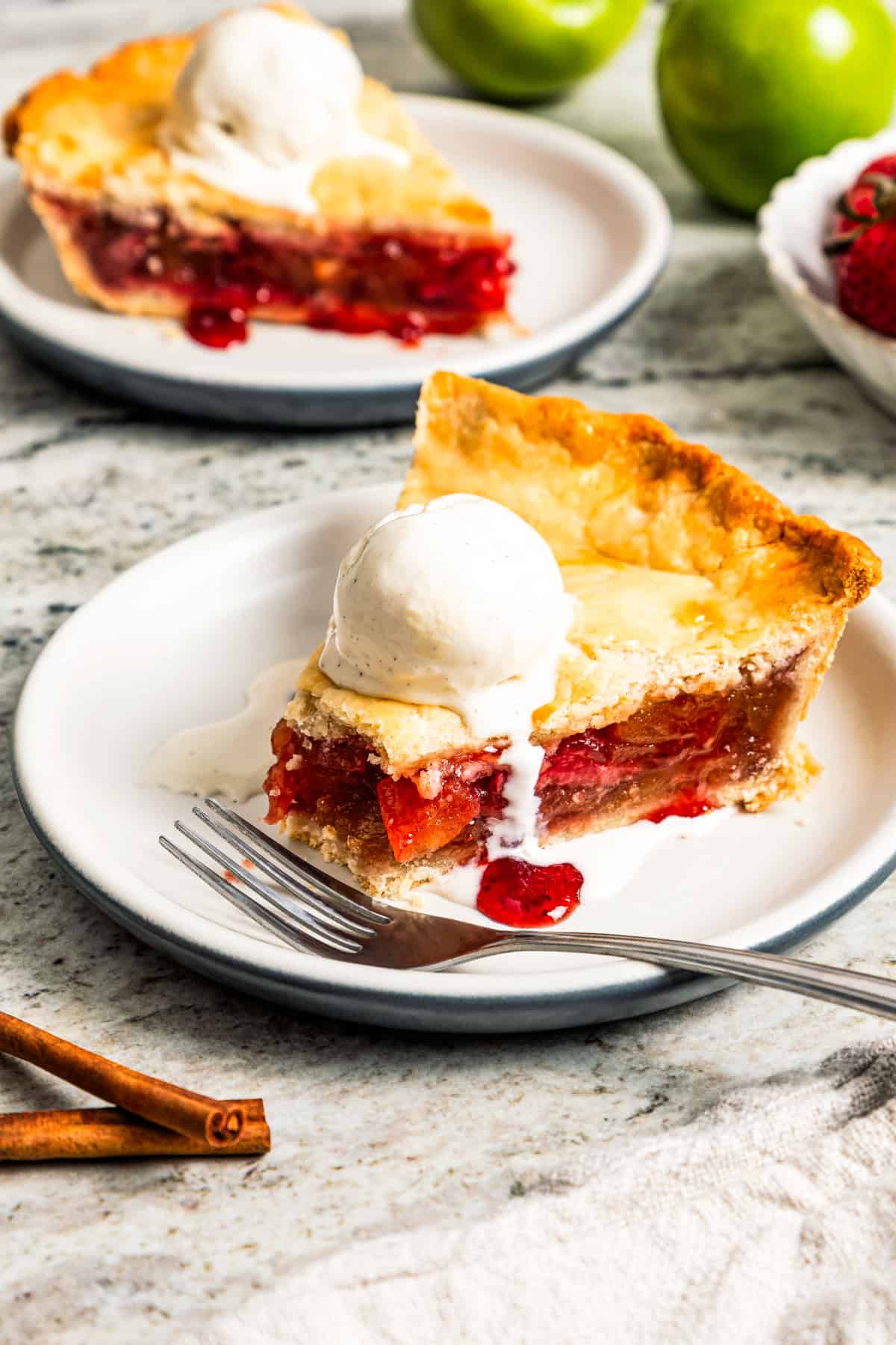 Apple berry pie is the perfect dessert to go from summer to fall! A cozy homemade apple pie bursting with fresh berries in a flaky pie crust. A slice of apple berry pie served on a dessert plate, with a forkful missing from the edge of the pie.