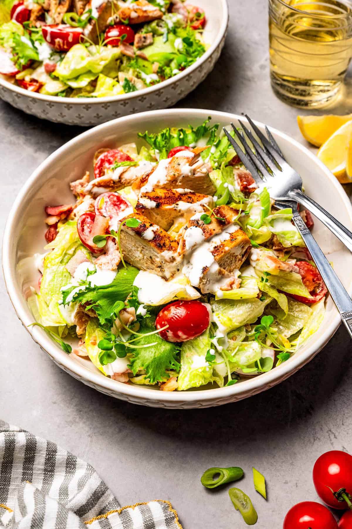 This easy BLT chicken salad combines juicy grilled chicken, crispy bacon, and ripe tomatoes with fresh lettuce and creamy yogurt dressing. A BLT chicken salad served in two large bowls.