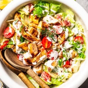 BLT grilled chicken salad in a bowl with salad tongs.